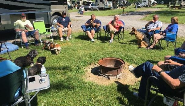 Group gathered in lawn chairs with a number of dogs outside a motorhome.